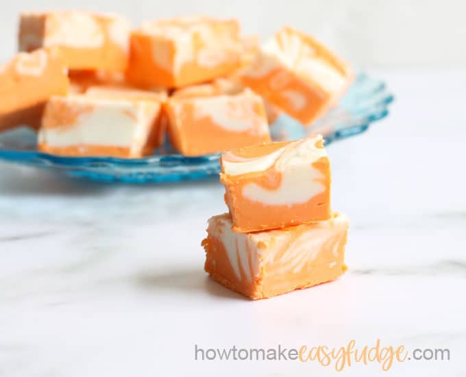 orange creamsicle fudge stacked on blue plate with white background