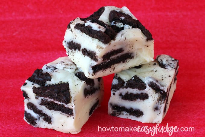 3 squares of cookies and cream fudge filled with OREO cookies on a red background