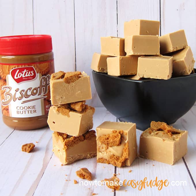 a jar of Biscoff Cookie Butter set next to a stack of Biscoff Fudge topped with Biscoff Cookie pieces alongside a black bowl filled with plain Biscoff fudge