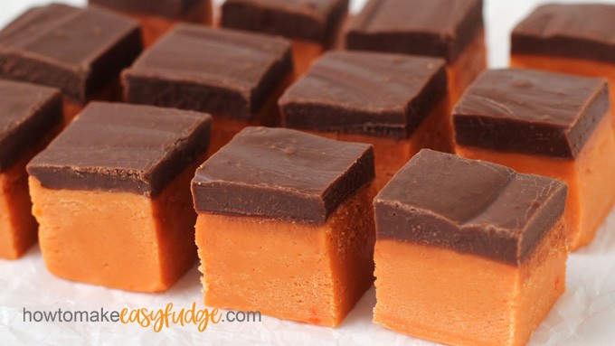 squares of orange and brown butterfinger fudge in rows on a wrinkled piece of parchment paper