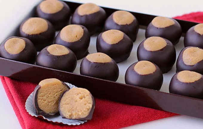 chocolate peanut butter fudge buckeyes in a brown box on a red napkin