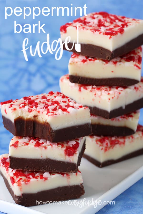 squares of peppermint bark fudge with a layer of chocolate fudge topped with a layer of white chocolate mint fudge sprinkled with crushed candy canes are stacked up on a blue snowflake background