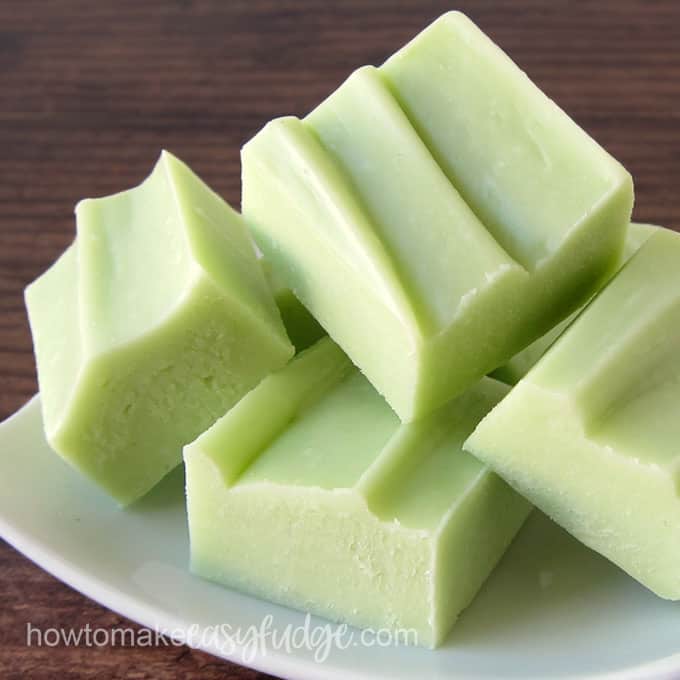 squares of pastel green key lime fudge on a small, square, white plate on a dark brown background