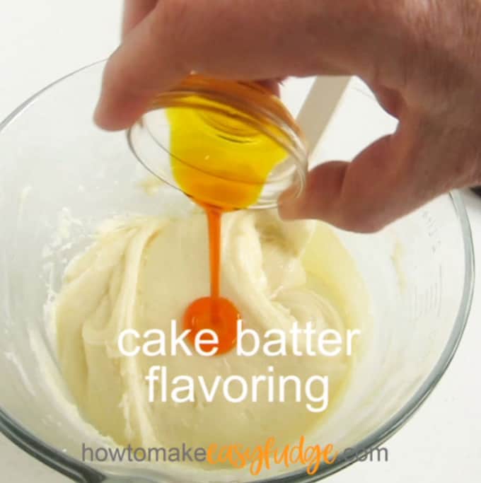 pouring cake batter flavoring over white chocolate fudge