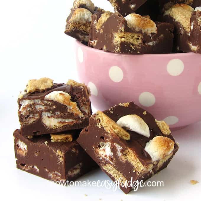 Toasted marshmallow and graham cracker topped s'mores fudge sitting on a white table and in a pink and white polka dot bowl. 