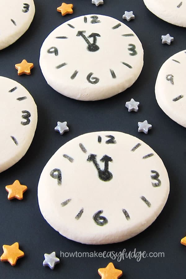 White chocolate fudge countdown clocks for a New Year's Eve party are surrounded by gold and silver star sprinkles.