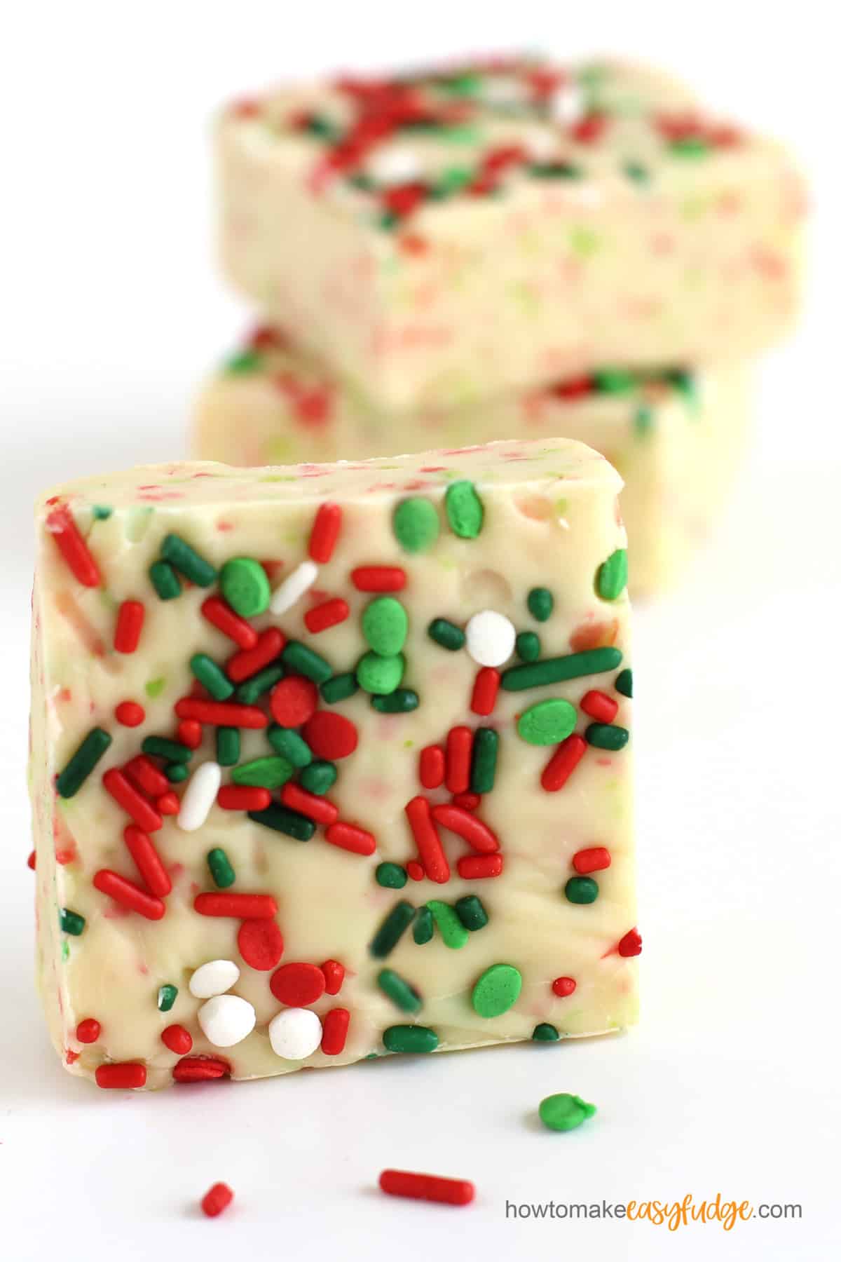 Red, white and green sprinkles on top of squares of sugar cookie fudge.