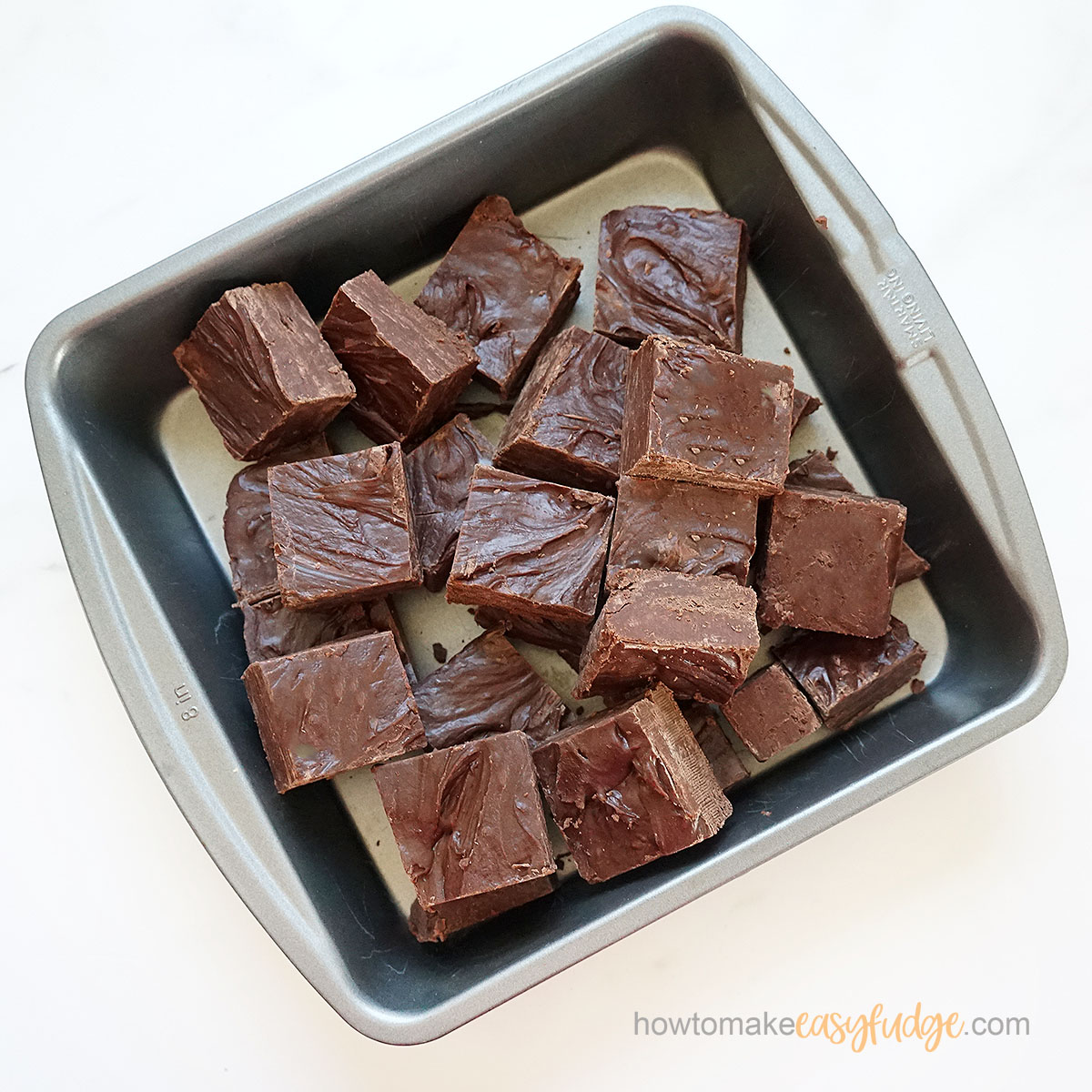 chocolate frosting fudge cut into squares sitting in an 8-inch square pan