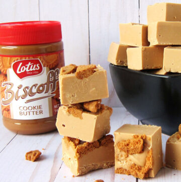 Biscoff fudge topped with Biscoff cookies stacked next to a jar of Biscoff cookie butter