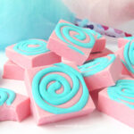 pink cotton candy fudge topped with a swirl of blue fudge set in front of cotton candy