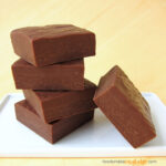 milk chocolate fudge squares stacked on a white plate