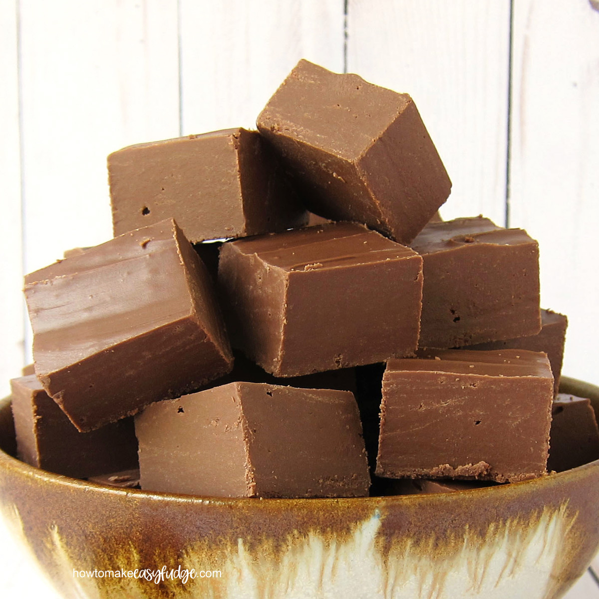 Squares of easy Nutella fudge stacked in a handmade earthenware bowl