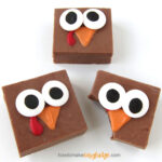 Thanksgiving fudge turkeys with big candy eyes, an orange candy beak, and red wattle