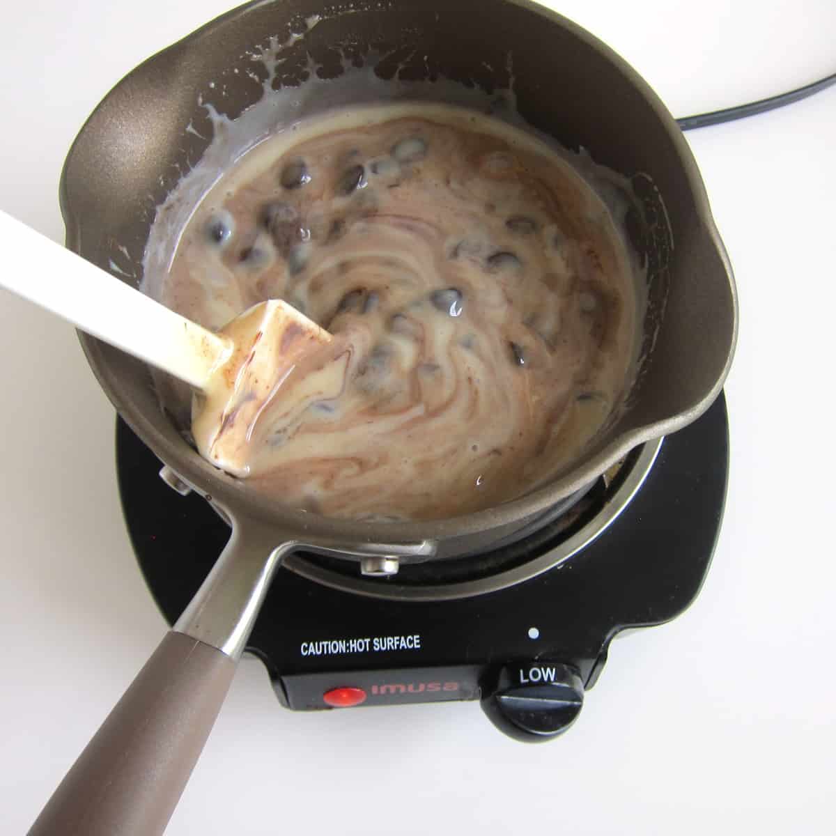 Stirring the melted chocolate chips and sweetened condensed milk together.