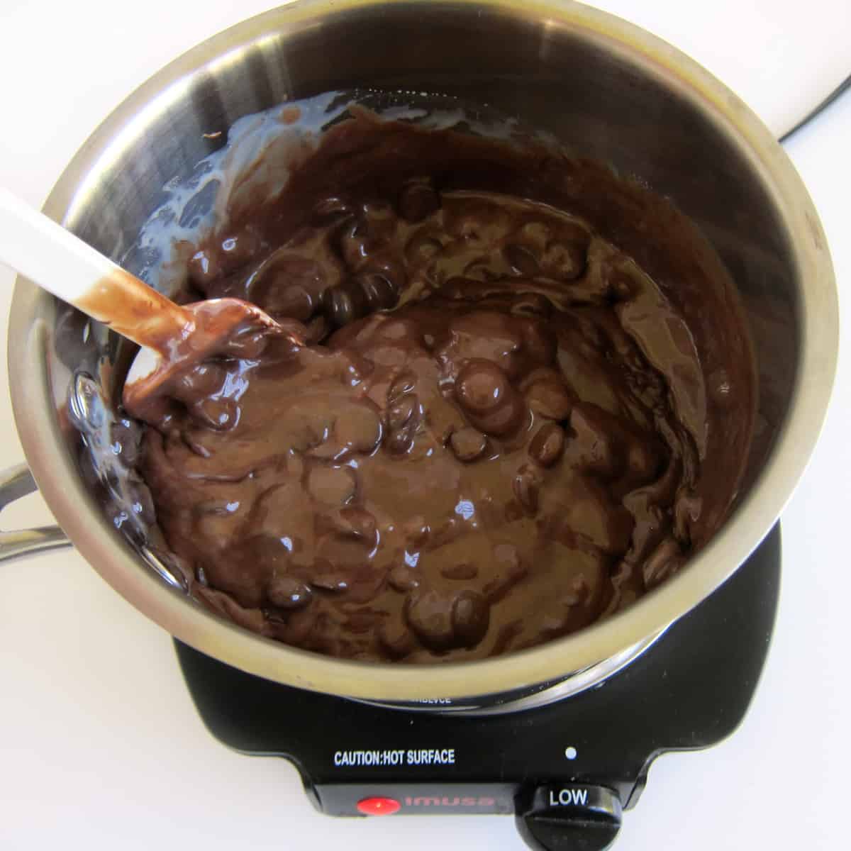melting chocolate chips and sweetened condensed milk in saucepan on a hot plate over low heat