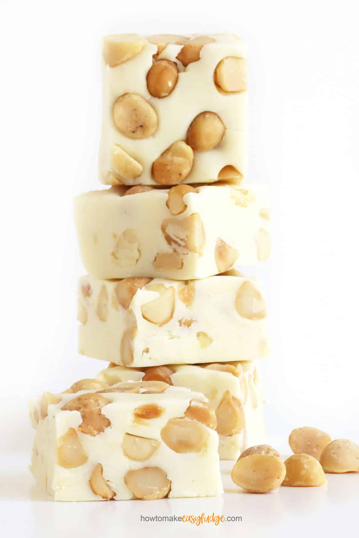 easy white chocolate macadamia nut fudge stacked up next to macadamia nuts