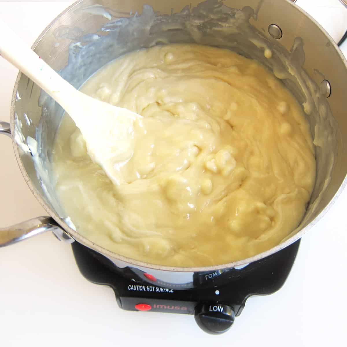 Melting white chocolate chips and sweetened condensed milk in a saucepan over low heat.