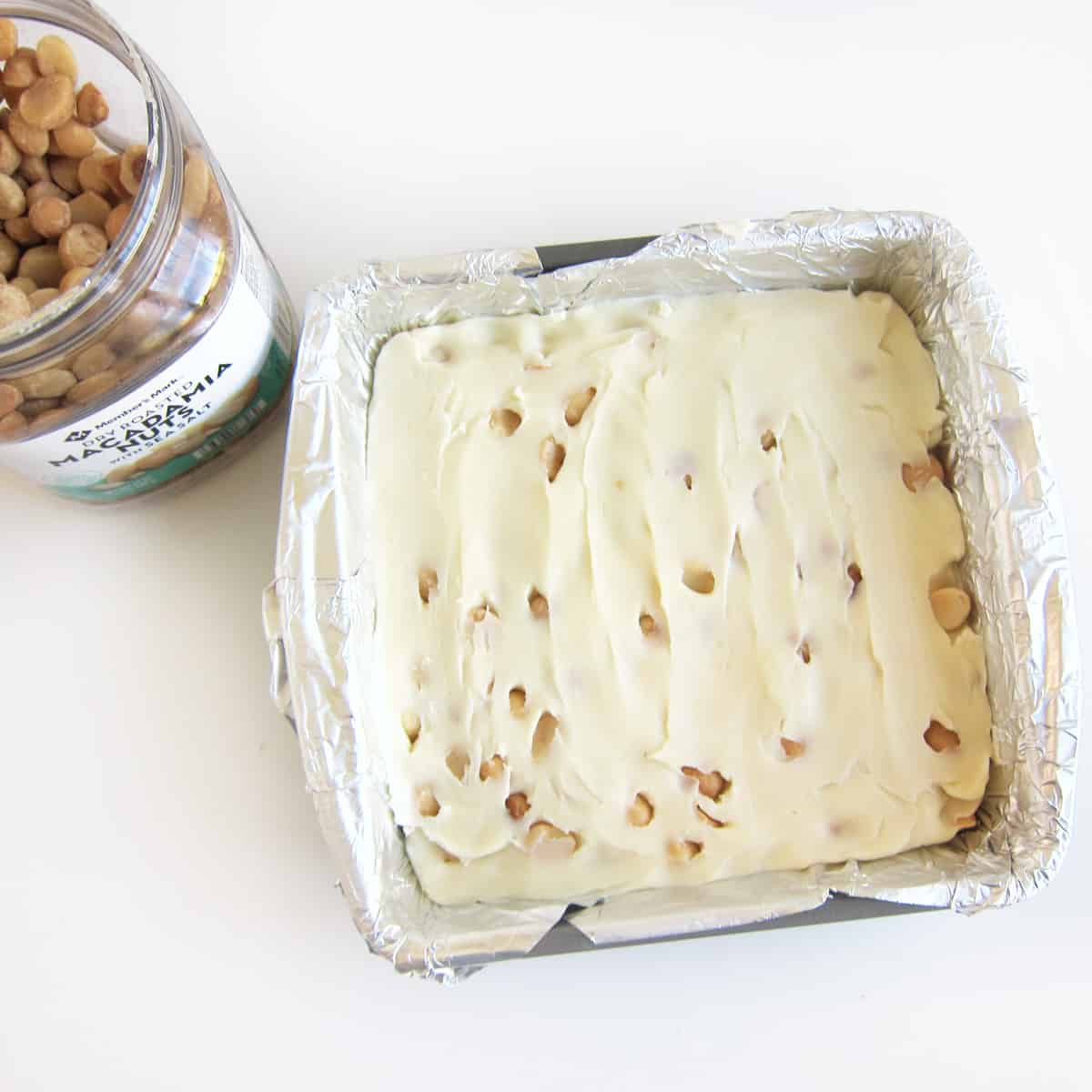 white chocolate fudge with macadamia nuts in a foil-lined pan