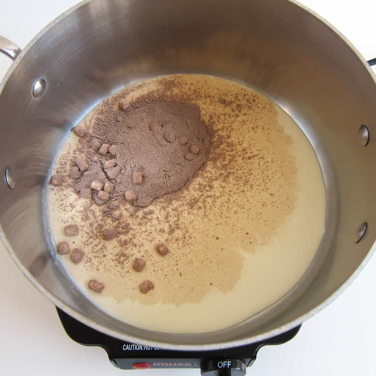 hot cocoa mix with marshmallows and heavy whipping cream in a saucepan.