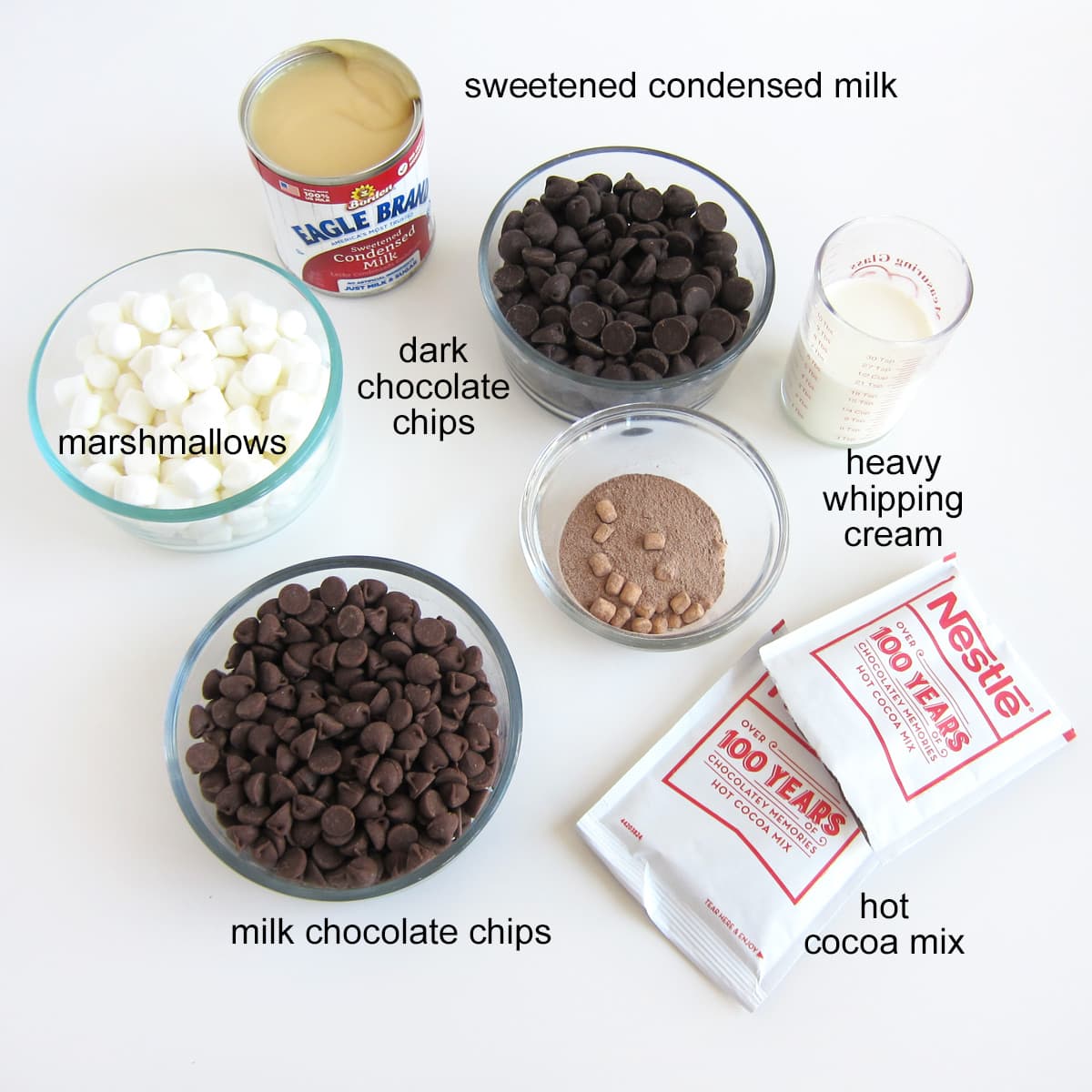 hot chocolate fudge ingredients including hot cocoa mix, dark chocolate, milk  chocolate, mini marshmallows, sweetened condensed milk, and heavy whipping cream.