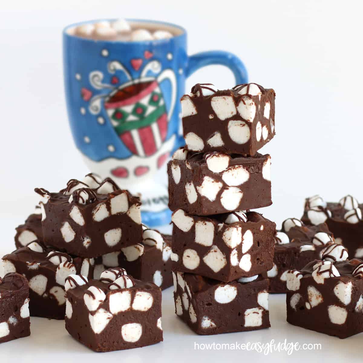 hot chocolate fudge filled with mini marshmallows arranged in front of a mug of hot cocoa.