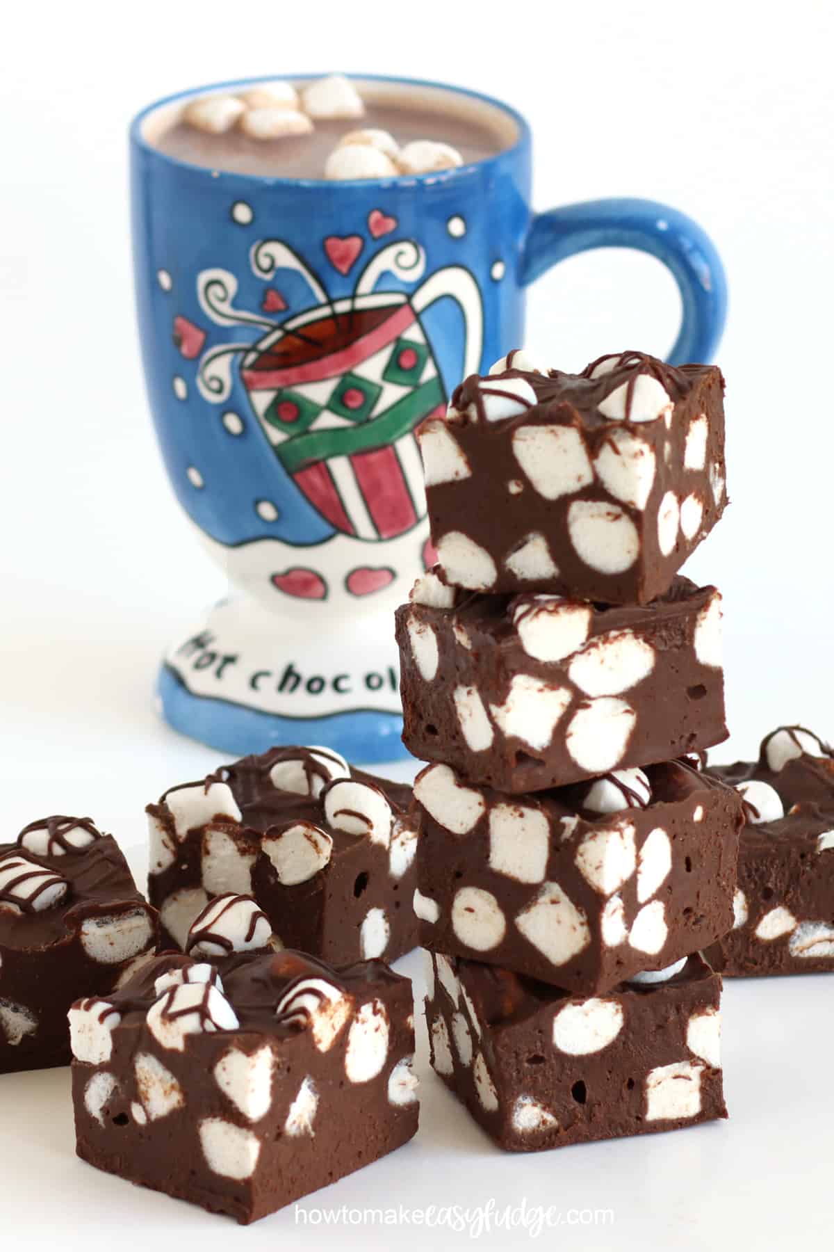 hot cocoa fudge filled with marshmallows set next to a mug of hot chocolate.