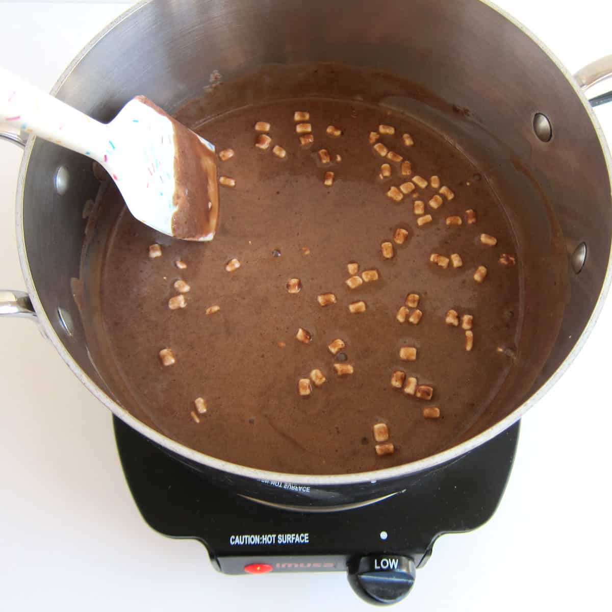 hot cocoa mix stirring into heavy cream in a saucepan.